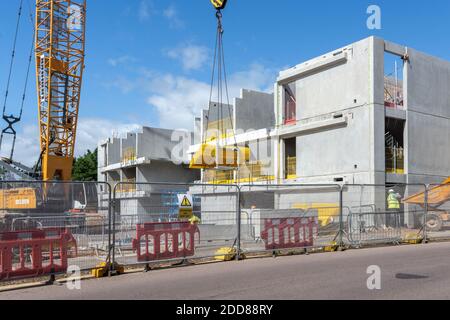 Un rack de sections de barrière de sécurité à fil jaune en cours de levage et est manourévérée par une grue derrière une clôture de sécurité sur un site de construction d'une nouvelle voiture à plusieurs étages Banque D'Images