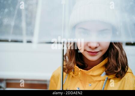 Fille portant un imperméable cache-visage sous un parapluie à l'extérieur Banque D'Images