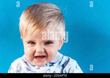 Bébé souriant debout contre le mur bleu Banque D'Images