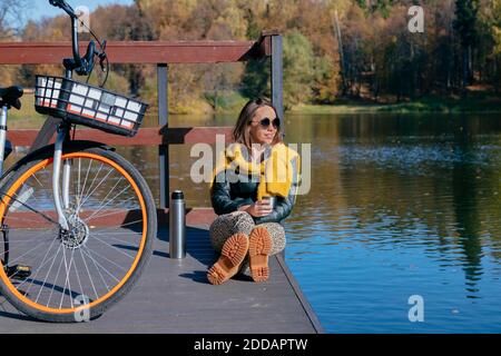 Femme prenant un café tout en se relaxant sur la jetée au-dessus du lac Banque D'Images