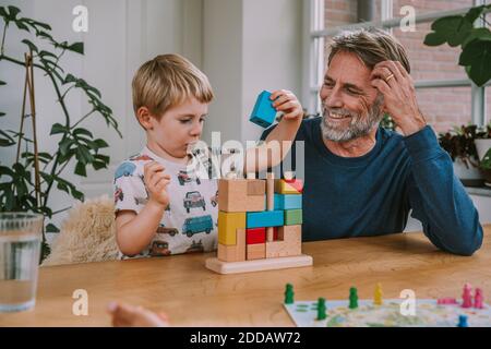 Père regardant son fils jouer avec le puzzle tout en étant assis à la maison Banque D'Images