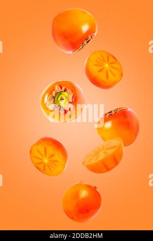 Fruits volants isolés. Sept morceaux de kaki tombant sur fond coloré créatif avec le chemin d'écrêtage comme élément de conception de paquet et de la publicité. Complet Banque D'Images