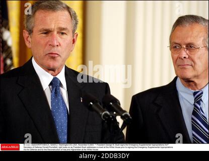 PAS DE FILM, PAS DE VIDÉO, PAS DE TV, PAS DE DOCUMENTAIRE - © STEVE DESLICH/KRT/ABACA. 52425-2. Washington-DC-États-Unis. Novembre 6 2003. Le président George W. Bush signe la Loi sur les crédits supplémentaires d'urgence, le secrétaire à la Défense Donald Rumsfeld, regarde à droite tandis que le président Bush s'adresse à une foule à la Maison Blanche Banque D'Images