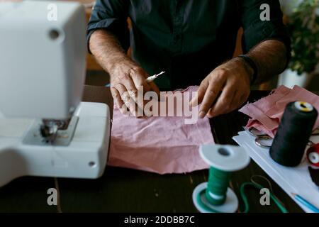 Homme mature tailleur avec tissu travaillant sur la table au travail studio Banque D'Images