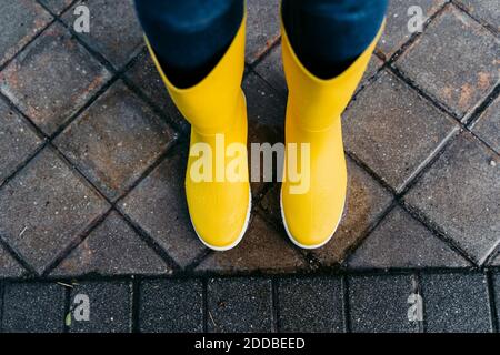 Femme portant des bottes jaunes debout dans la rue pendant la saison des pluies Banque D'Images
