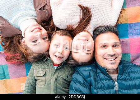 Juste au-dessus de la vue de la famille souriante couché sur le pique-nique couverture dans le parc Banque D'Images