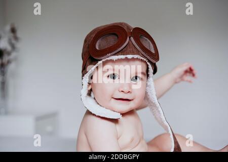 Bébé garçon mignon portant un capuchon aviateur lorsqu'il est assis à la maison Banque D'Images