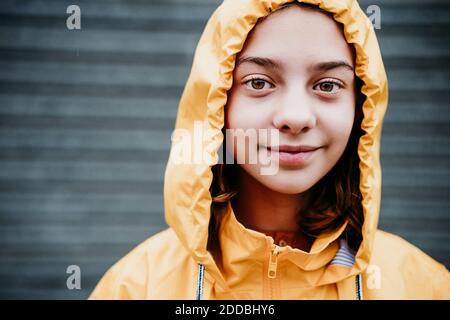 Fille souriante portant un imperméable debout à l'extérieur Banque D'Images