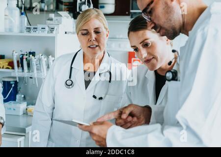 Homme et femme scientifique utilisant une tablette numérique tout en se tenant à laboratoire Banque D'Images