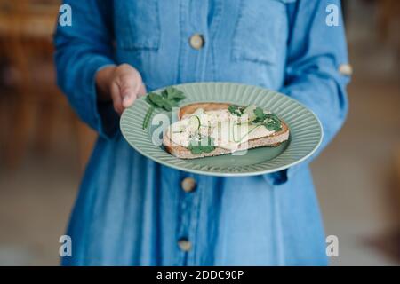 Section médiane de la femme propriétaire tenant bruschetta pendant qu'elle se tient dans le café Banque D'Images