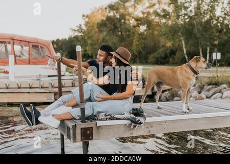 Couple admirant la vue tout en étant assis près d'un chien debout jetée Banque D'Images