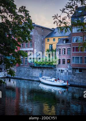 Belgique, province de Namur, Namur, bateau à moteur amarré le long du canal de la ville s'étendant devant une rangée de maisons de ville Banque D'Images