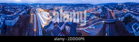 Allemagne, Rhénanie-du-Nord-Westphalie, Wuppertal, Panorama de la gare Hauptbahnhof de Wuppertal et des bâtiments de la ville environnante au crépuscule Banque D'Images