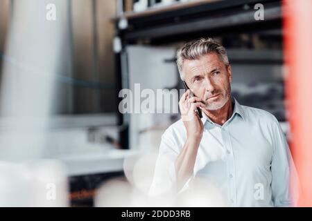 Un ingénieur qui envisage de regarder loin tout en parlant avec un smartphone usine Banque D'Images