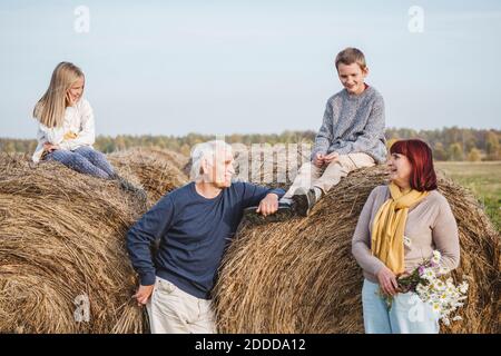 Grands-parents avec petits-enfants assis sur des balles de foin Banque D'Images