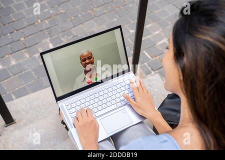 Des appels vidéo d'une femme d'affaires via un ordinateur portable tout en étant assise sur des marches Banque D'Images