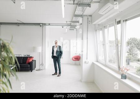 Homme d'affaires avec les mains dans les poches debout à nouveau bureau Banque D'Images