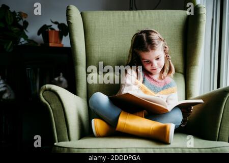 Une fille qui fait ses devoirs tout en étant assise sur une chaise à la maison Banque D'Images