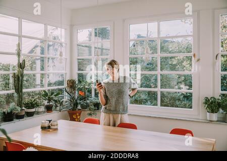 Femme utilisant un smartphone avec la main sur la hanche accueil Banque D'Images