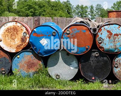 Anciens barils de pétrole brut. Des barils rouillés empilés sur l'herbe près de la clôture. Été, jour, couleurs vives. Banque D'Images