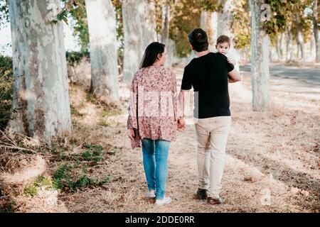 Couple avec bébé tenant les mains tout en marchant à l'extérieur Banque D'Images