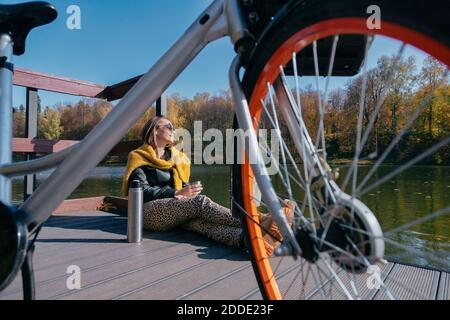 Femme se détendant à vélo sur la jetée au-dessus du lac pendant le week-end Banque D'Images