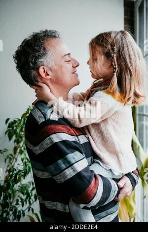 Père regardant la fille en portant les bras à la maison Banque D'Images