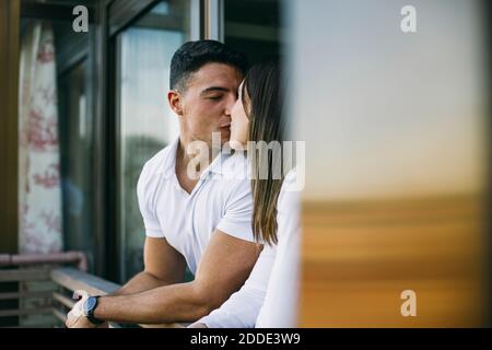 Couple s'embrassant en se tenant sur le balcon Banque D'Images