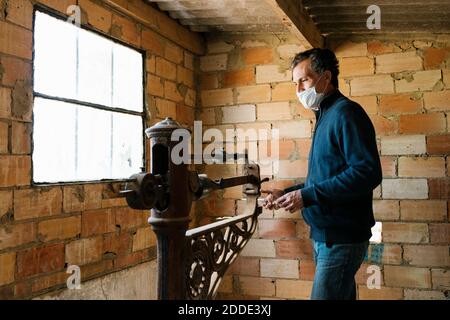 Travailleur portant un masque de protection pesant les raisins sur une balance à l'ancienne à cave de vinification Banque D'Images