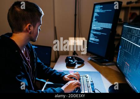 Hacker mâle regardant l'ordinateur pendant son travail au bureau Banque D'Images