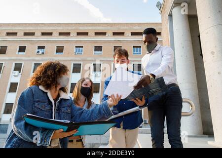 Les élèves de sexe masculin et féminin portent un masque de sécurité lorsqu'ils discutent à l'intérieur campus universitaire Banque D'Images