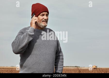 Agriculteur parlant au téléphone mobile en se tenant à la ferme Banque D'Images