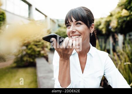 Bonne femme d'affaires qui regarde loin en parlant sur un téléphone portable Banque D'Images