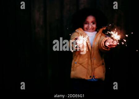 Fille debout et tenant feu de sparkler la nuit Banque D'Images