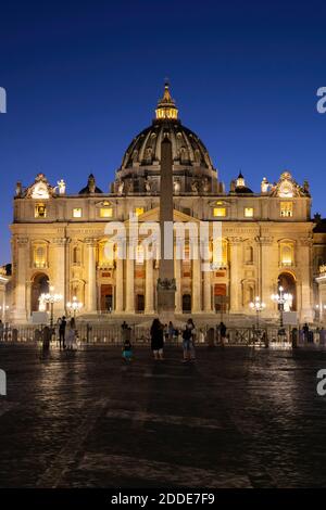 Touristes à la place Saint-Pierre avec la basilique Saint-Pierre illuminée contre le ciel bleu clair la nuit, Cité du Vatican, Rome, Italie Banque D'Images