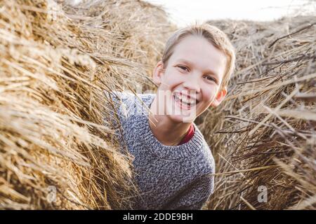 Un garçon joyeux qui se délasser de haystack Banque D'Images