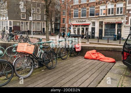 Amsterdam, pays-Bas - Mars 2020 : l'homme sans domicile dort sous une couverture rouge dans le centre de la ville européenne. Banque D'Images