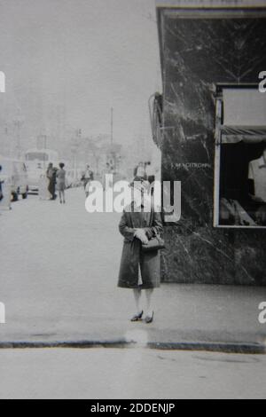 Belle photographie en noir et blanc vintage des années 1970 d'une femme marchant dans la rue. Banque D'Images