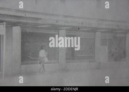 Belle photographie en noir et blanc vintage des années 1970 d'une femme marchant dans la rue. Banque D'Images