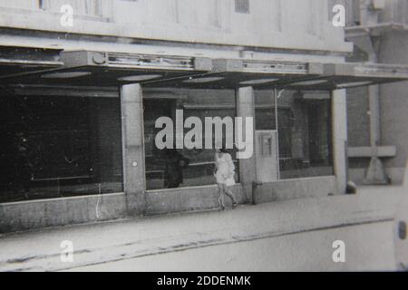 Belle photographie en noir et blanc vintage des années 1970 d'une femme marchant dans la rue. Banque D'Images