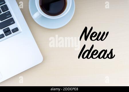 TEXTE DE NOUVELLES IDÉES avec ordinateur portable et tasse de café sur fond de bois. Concept d'espace de travail et de copie. Banque D'Images