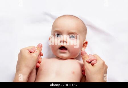 Maman fait un massage des mains d'enfant caucasien jusqu'à un an. Gymnastique pour les petits enfants. Gros plan. Vue de dessus. Banque D'Images