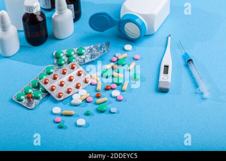 Différents médicaments médicaux, thermomètre, seringue, vaporisateur, flacons de gouttes, sirop, comprimés colorés dispersés, capsules Banque D'Images