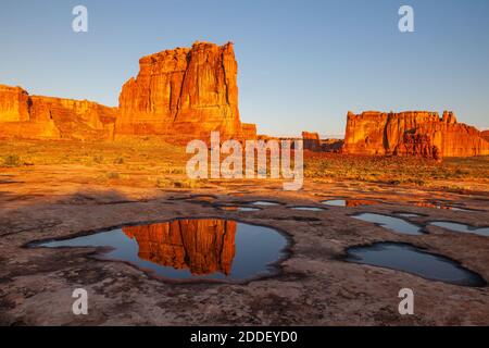 Les tours du palais de justice se reflètent dans une flaque le matin, dans le parc national d'Arches, Utah Banque D'Images