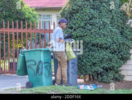 Alberton, Afrique du Sud - des personnes non identifiées creusent dans des poubelles résidentielles pour la nourriture et les articles utiles Banque D'Images