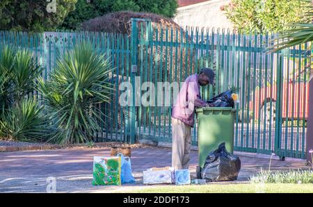 Alberton, Afrique du Sud - des personnes non identifiées creusent dans des poubelles résidentielles pour la nourriture et les articles utiles Banque D'Images
