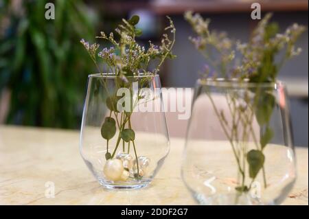 petites branches de petites fleurs séchées dans un vase en verre sur la table dans un restaurant Banque D'Images
