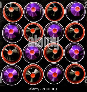 Vue aérienne des capsules noires, violettes et rouges disposées en quadrillage carré, isolée sur fond noir. Banque D'Images