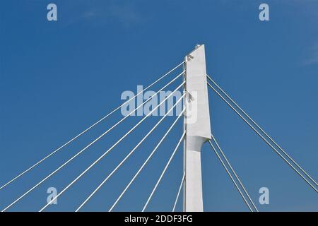 Un pilier en béton avec des câbles de suspension en fer isolés sur un fond bleu ciel. Banque D'Images