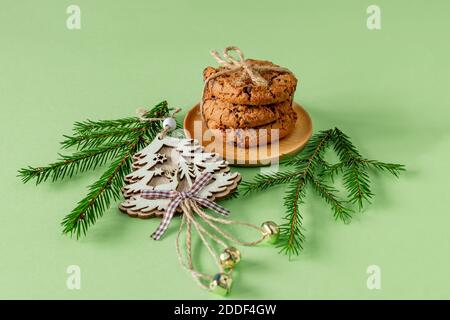 Composition de Noël avec biscuits aux pépites de chocolat sur papier vert avec branches de sapin et jouet en bois. Carte de vœux de fête Banque D'Images